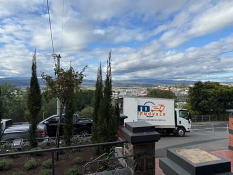 Removal truck overlooking suburban valley beneath cloudy sky
