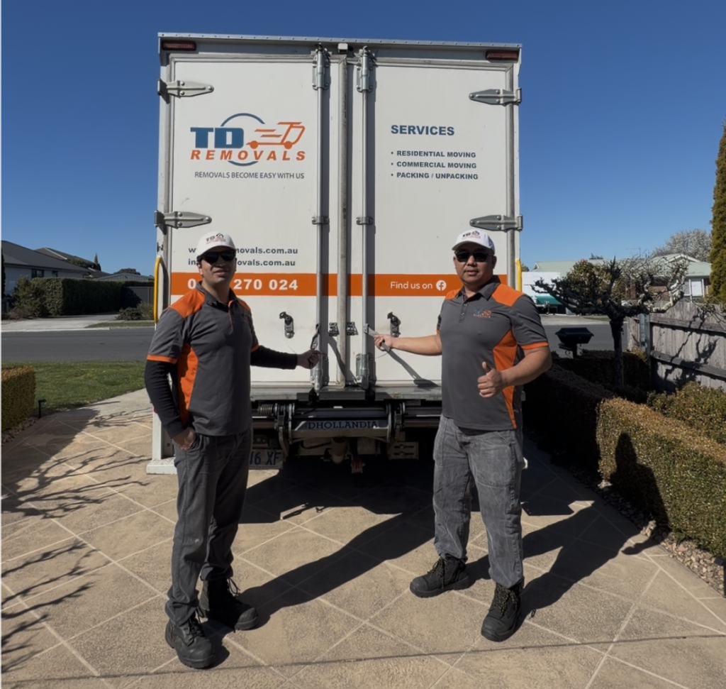 Two removalists beside TDD Removals truck in driveway