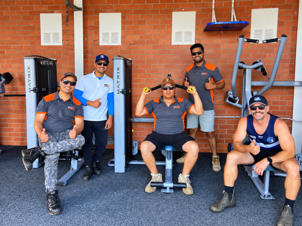 Five men pose with outdoor gym equipment