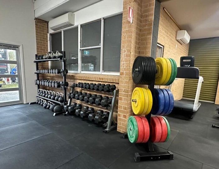 Gym weights and colourful bumper plates beside treadmill